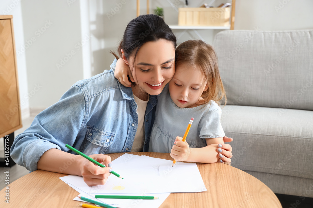 Young woman with her little daughter drawing at home