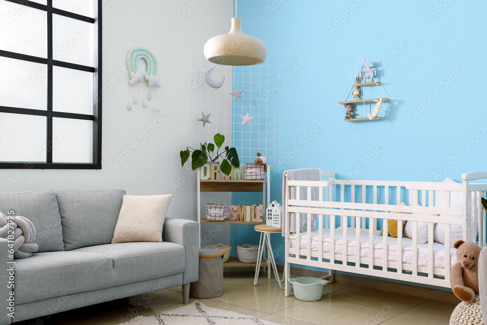 Interior of stylish bedroom with baby crib, sofa and shelving unit