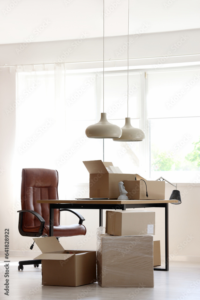 Interior of stylish office with cardboard boxes on moving day