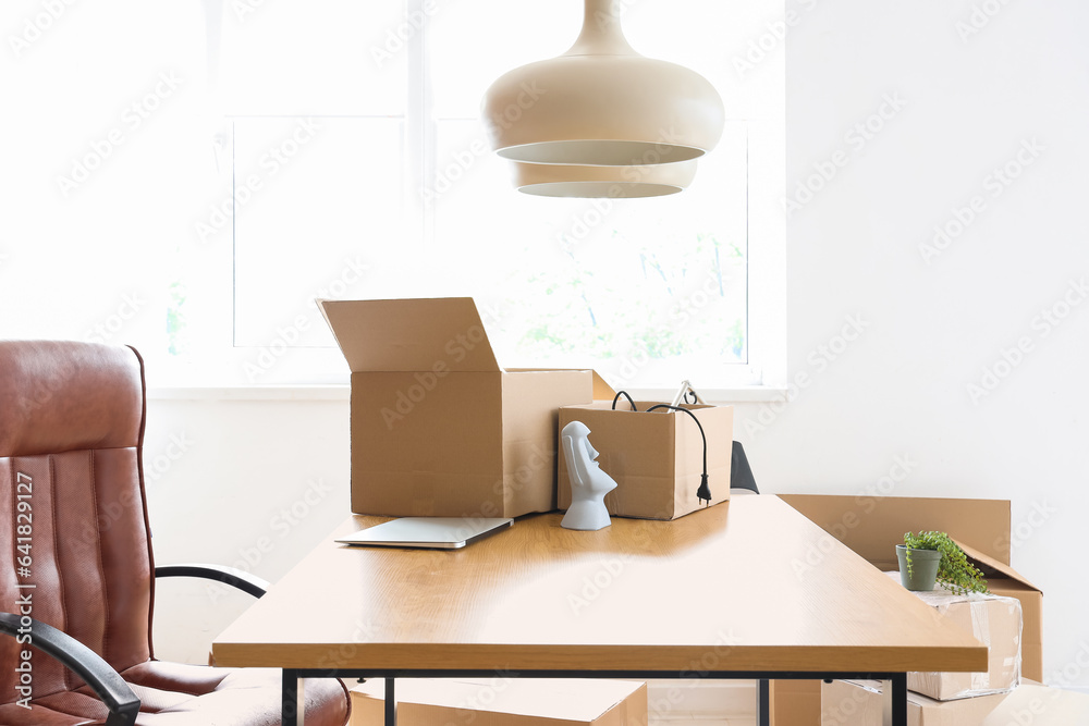 Cardboard boxes with personal belongings in office on moving day