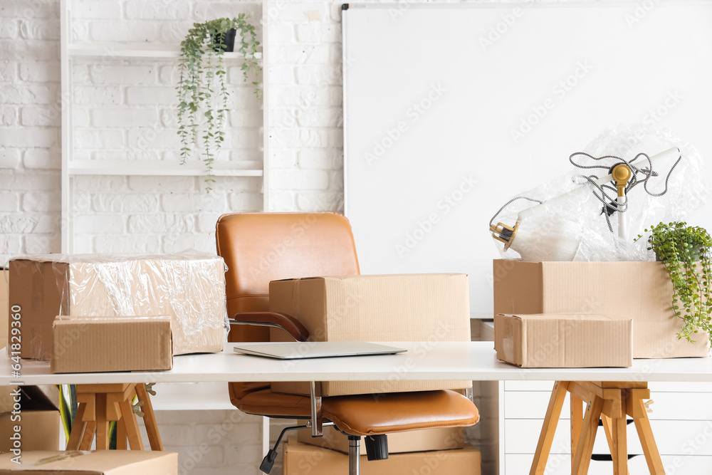 Modern workplace with laptop and cardboard boxes in office on moving day