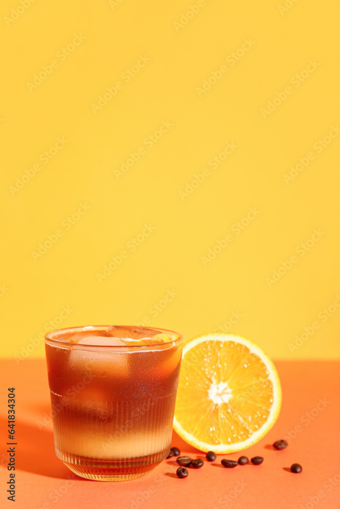 Glass of tasty orange espresso on color background