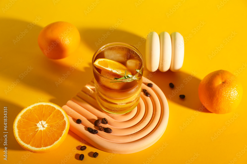 Glass of tasty orange espresso on yellow background