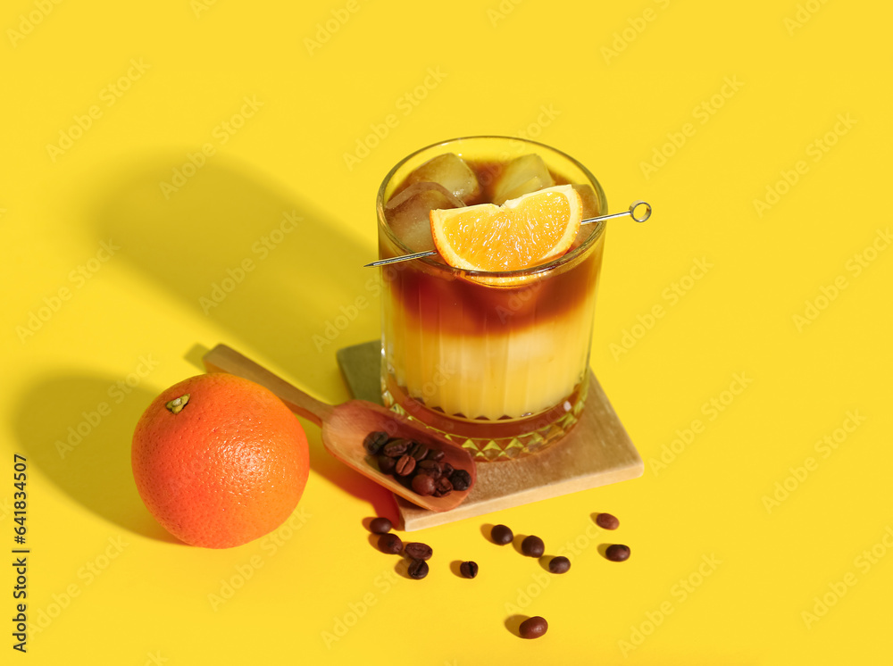 Glass of tasty orange espresso on yellow background