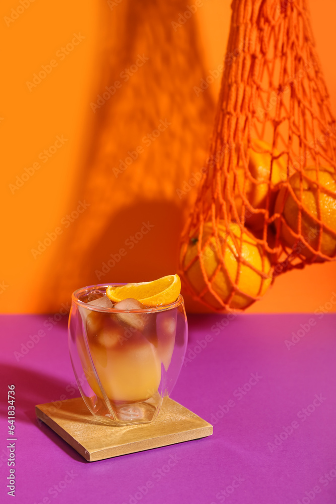 Glass of tasty orange espresso on color background