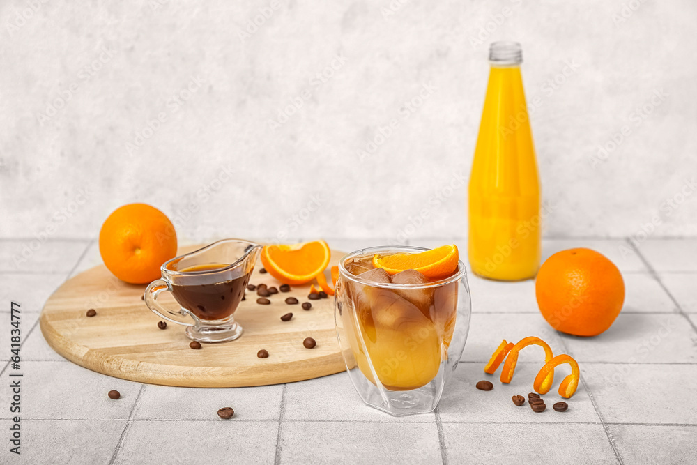 Glass of tasty orange espresso and ingredients on table