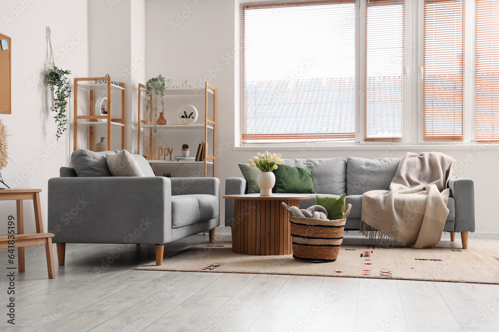 Interior of light living room with sofas, table and wicker basket