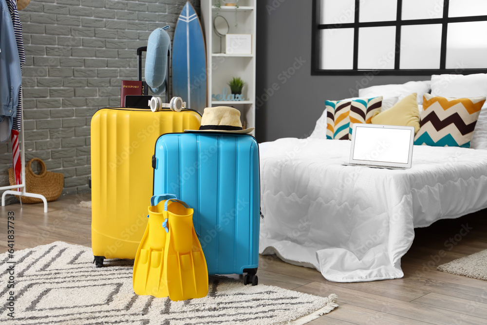 Suitcases with summer accessories in bedroom