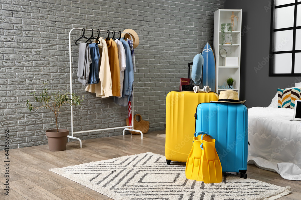 Suitcases with summer accessories in bedroom