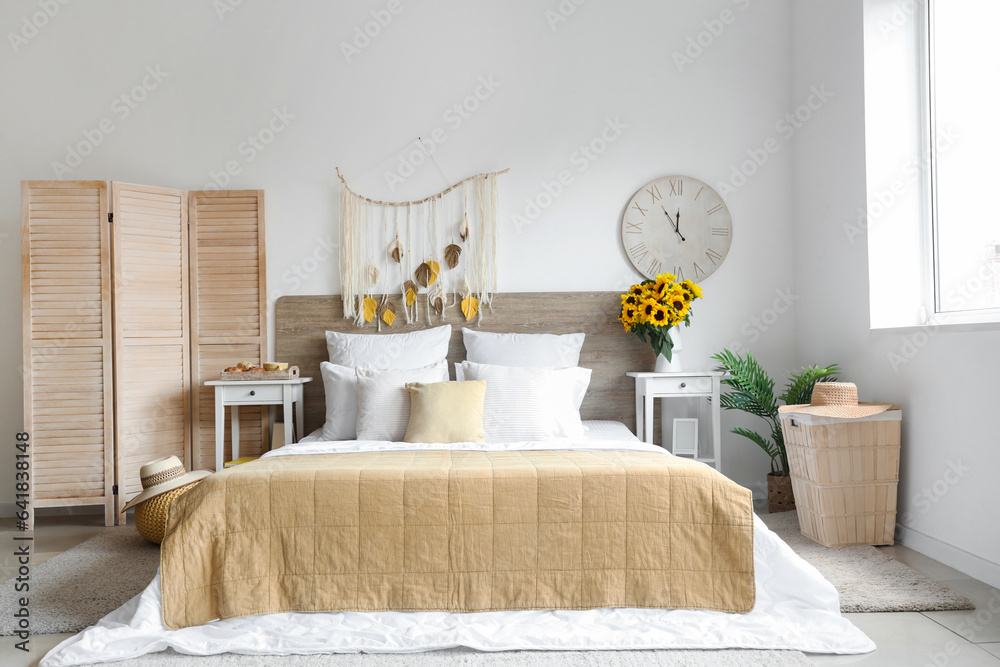 Interior of light bedroom with sunflowers in vase on table