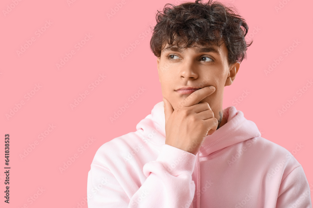 Portrait of pondering young man on pink background