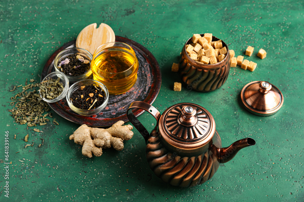 Composition with vintage brass tea set and different types of tea on green table