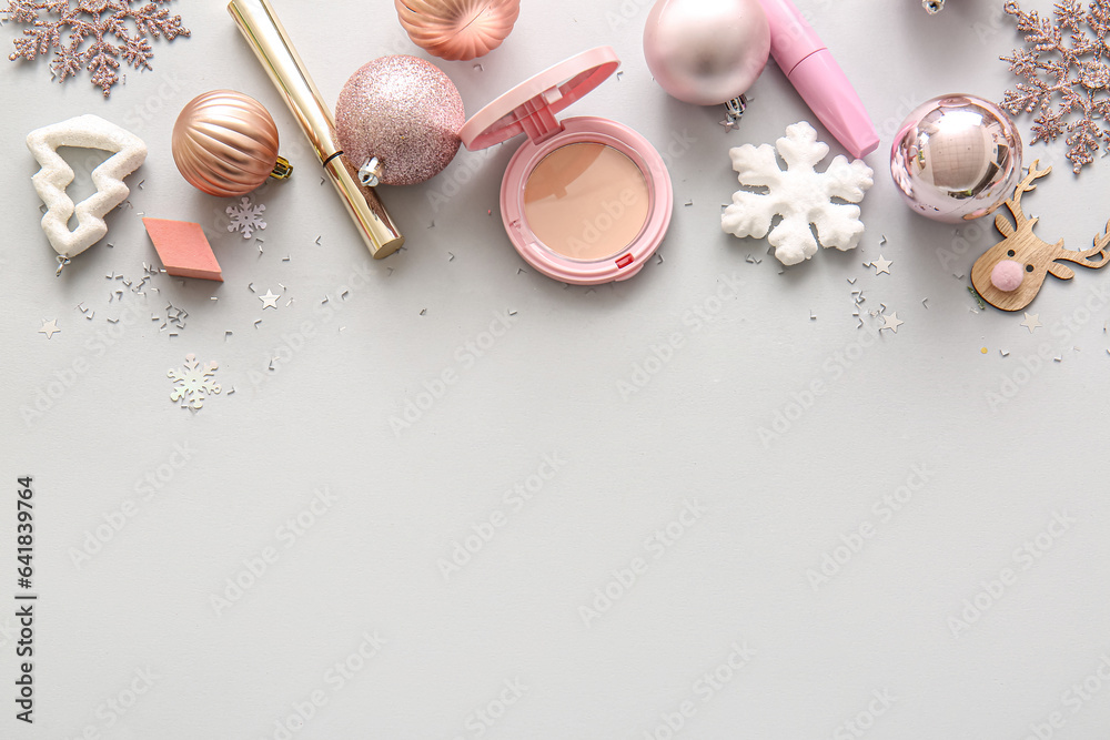 Beautiful pink Christmas decorations and makeup products on grey background