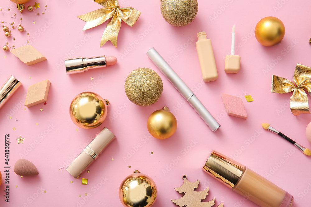 Beautiful golden Christmas decorations and makeup products on pink background