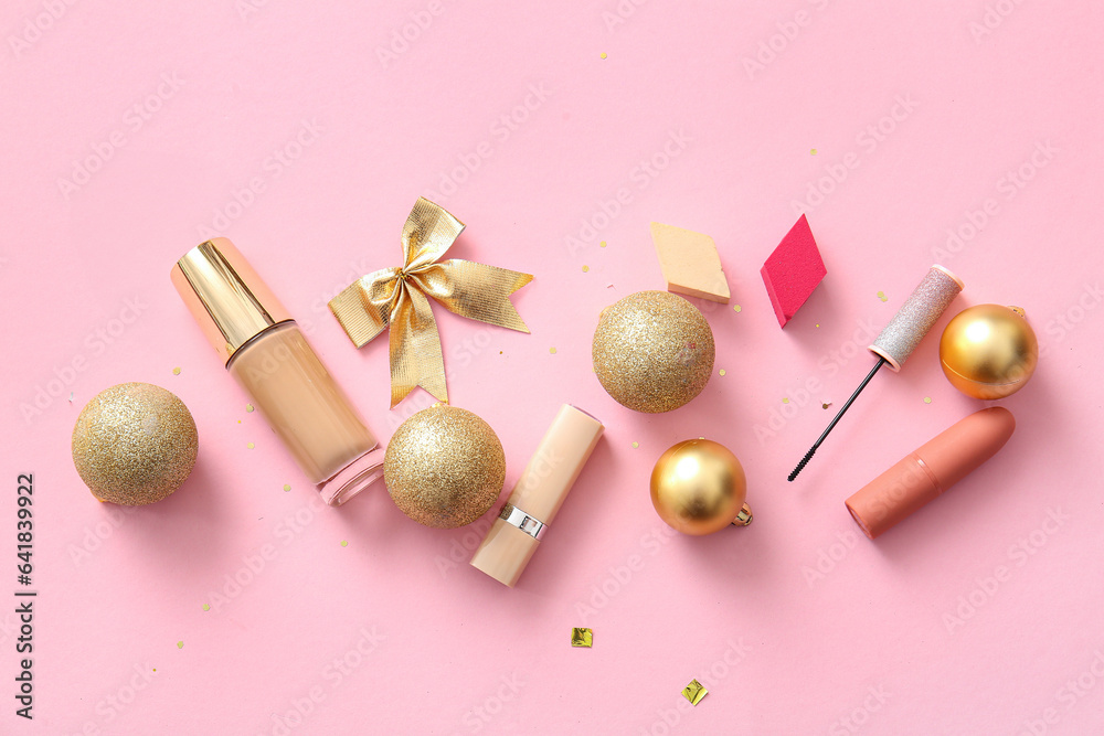 Beautiful golden Christmas decorations and makeup products on pink background