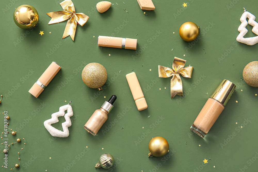 Composition with makeup products and golden Christmas decor on dark green background