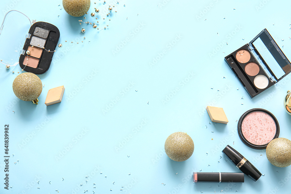 Composition with makeup products and golden Christmas balls on blue background