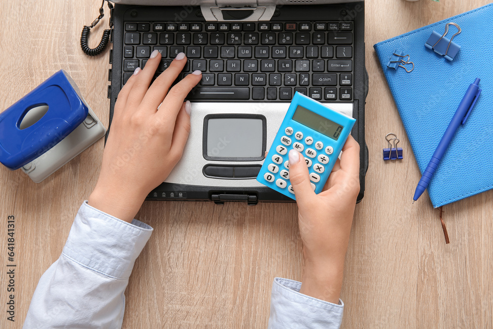 Woman working with old laptop at wooden table in office