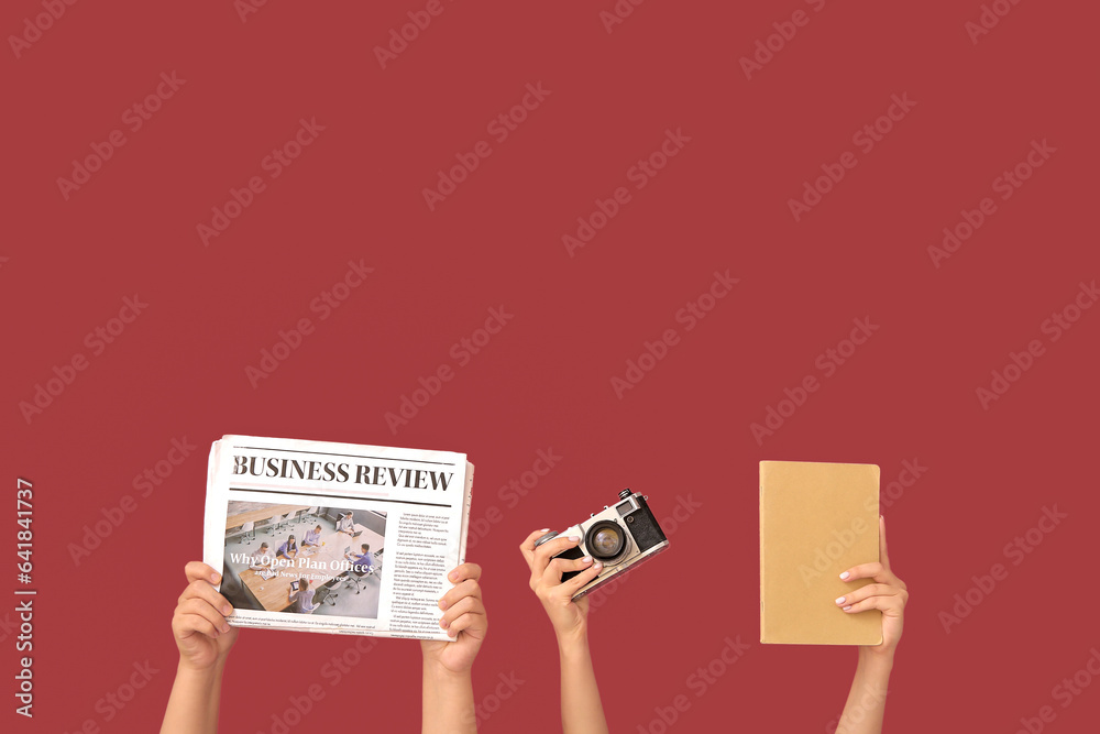 Female hands with newspaper, photo camera and notebook on color background