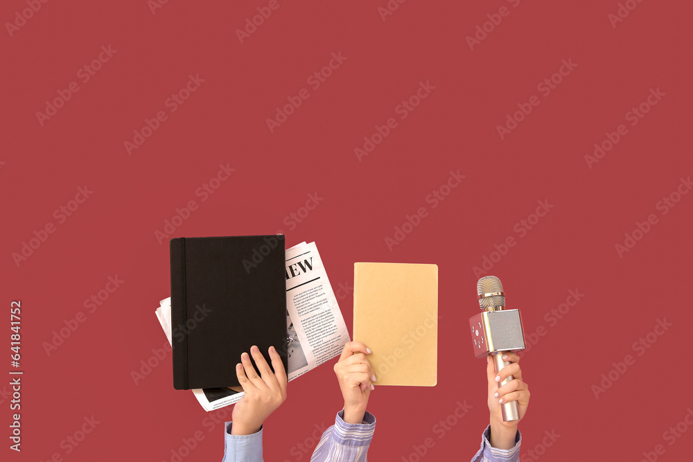 Female hands with notebooks, newspaper and microphone on color background