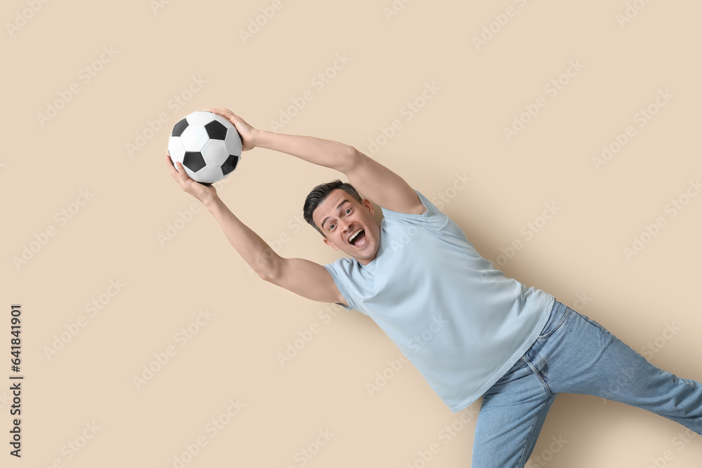 Handsome man with soccer ball on beige background