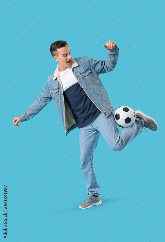 Young man playing with soccer ball on blue background