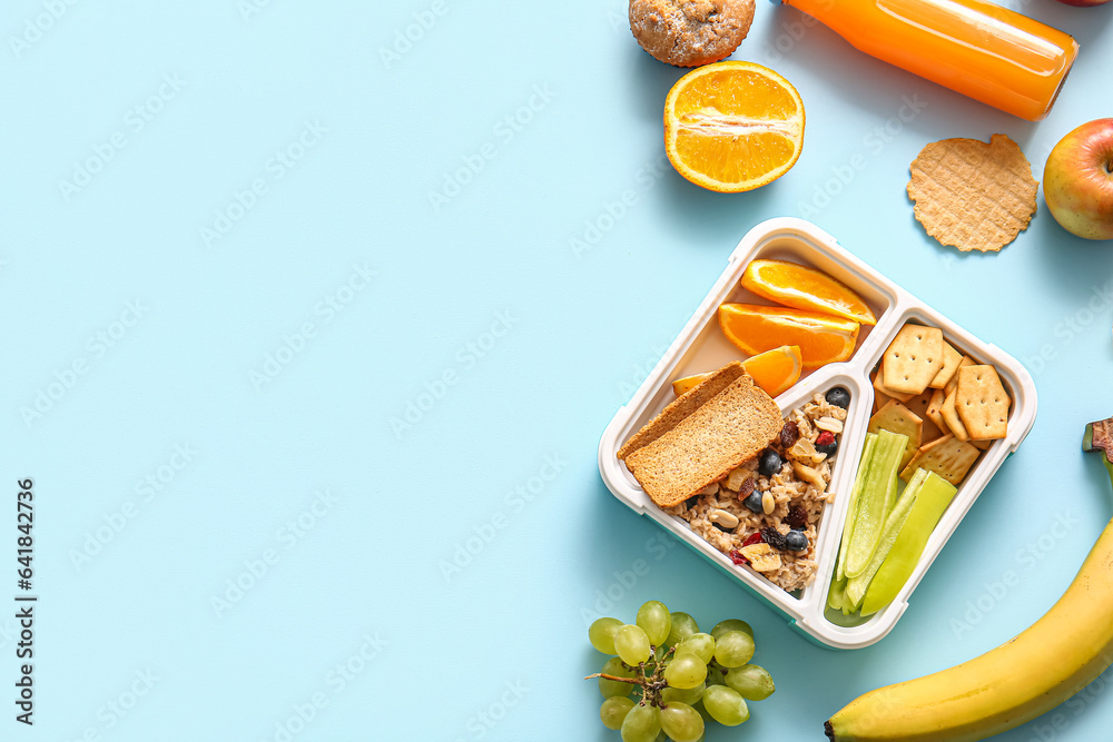 Lunchbox with delicious food and bottle of juice on blue background