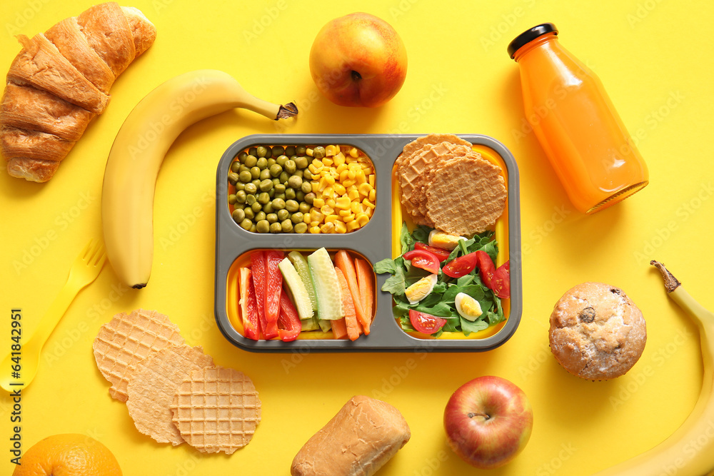 Lunchbox with delicious food and bottle of juice on yellow background