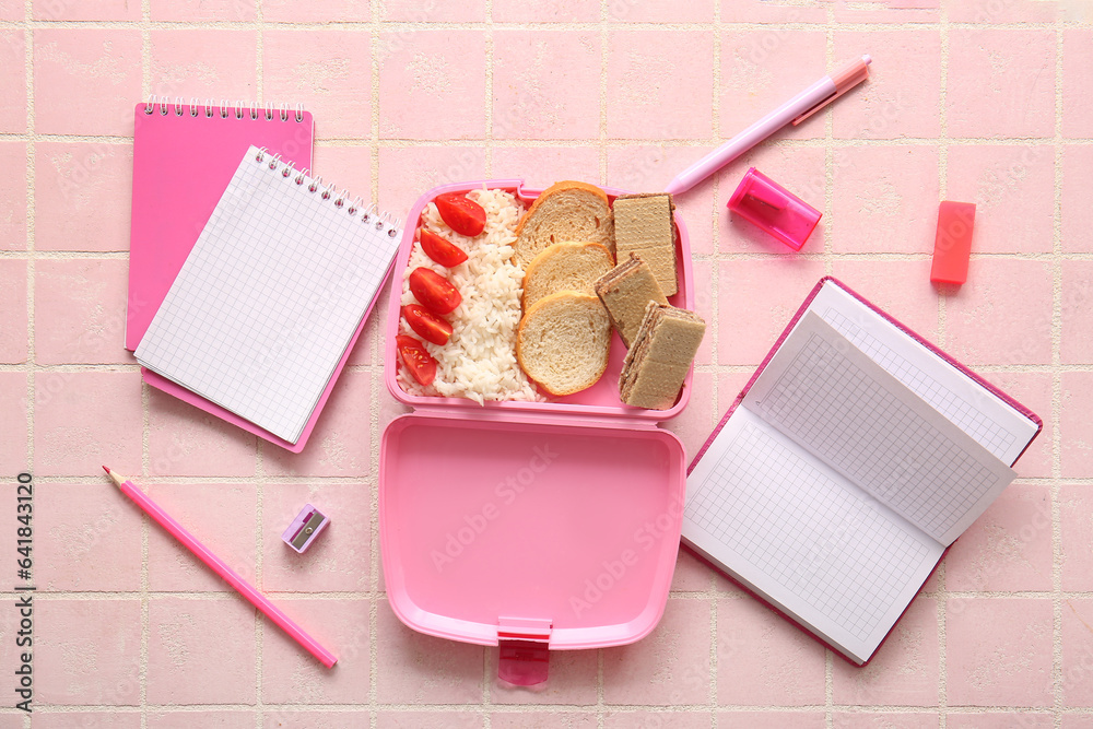 Lunchbox with delicious food and different stationery on pink tile background