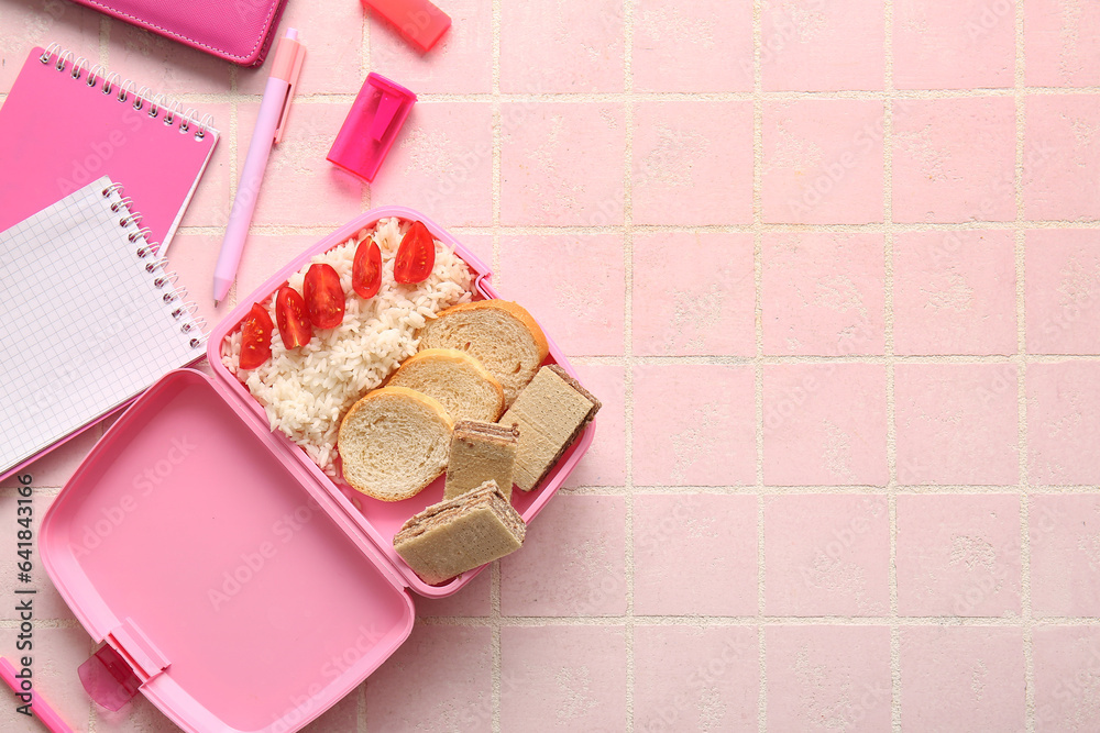 Lunchbox with delicious food and different stationery on pink tile background