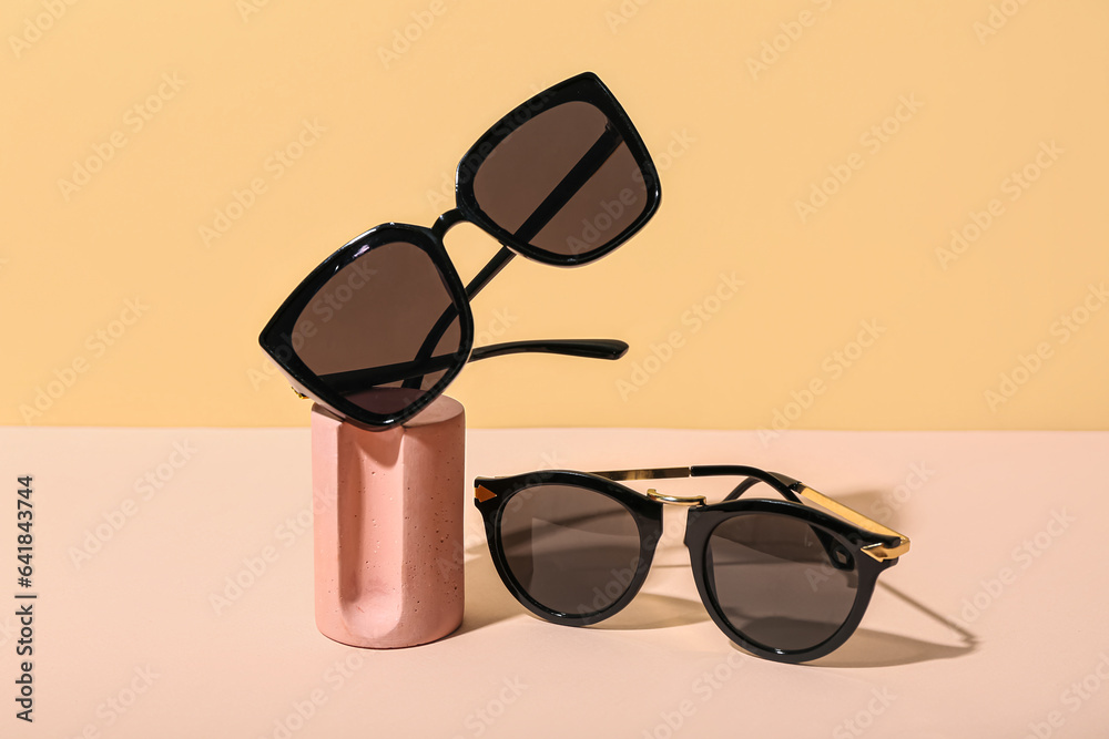 Decorative podium with stylish sunglasses on beige background