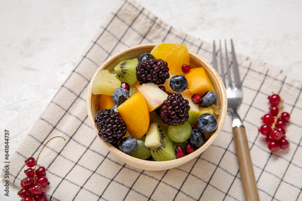 Bowl of fresh fruit salad on light background