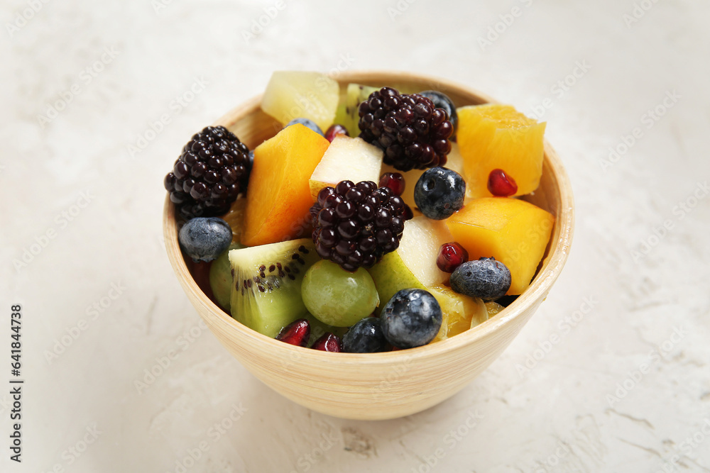 Bowl of fresh fruit salad on light background