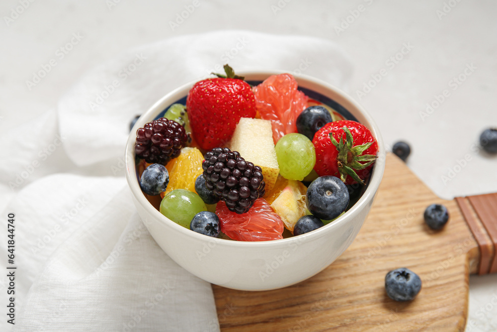 Bowl of fresh fruit salad on light background