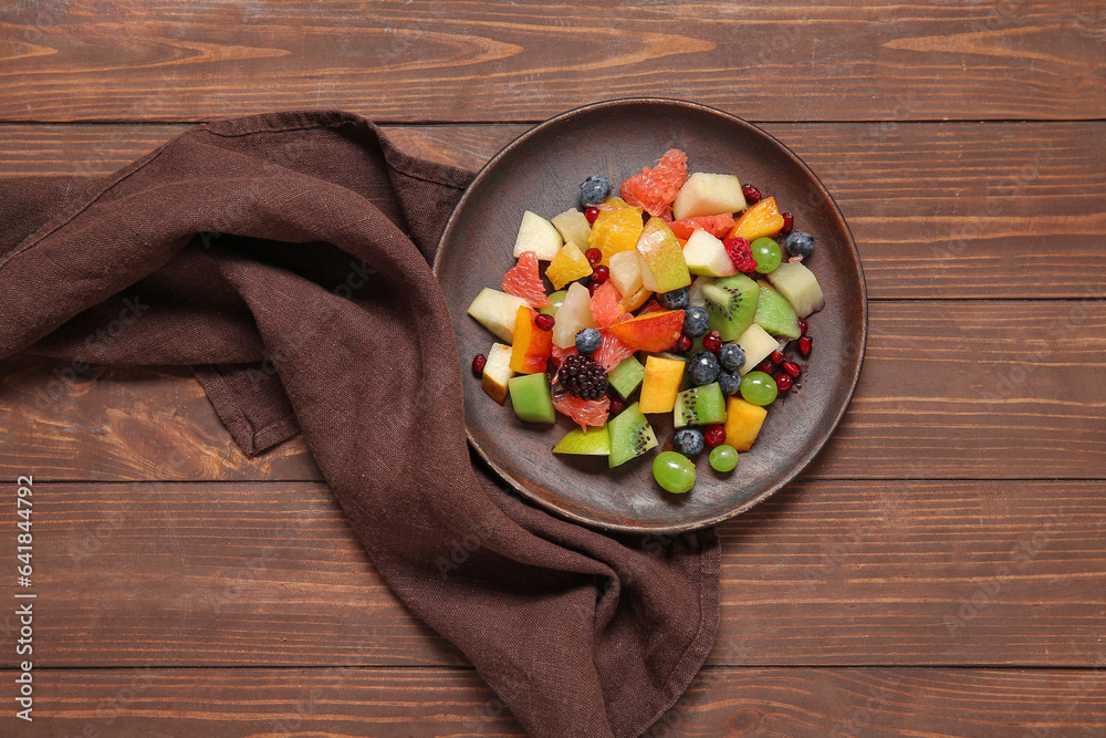 Plate of fresh fruit salad on wooden background