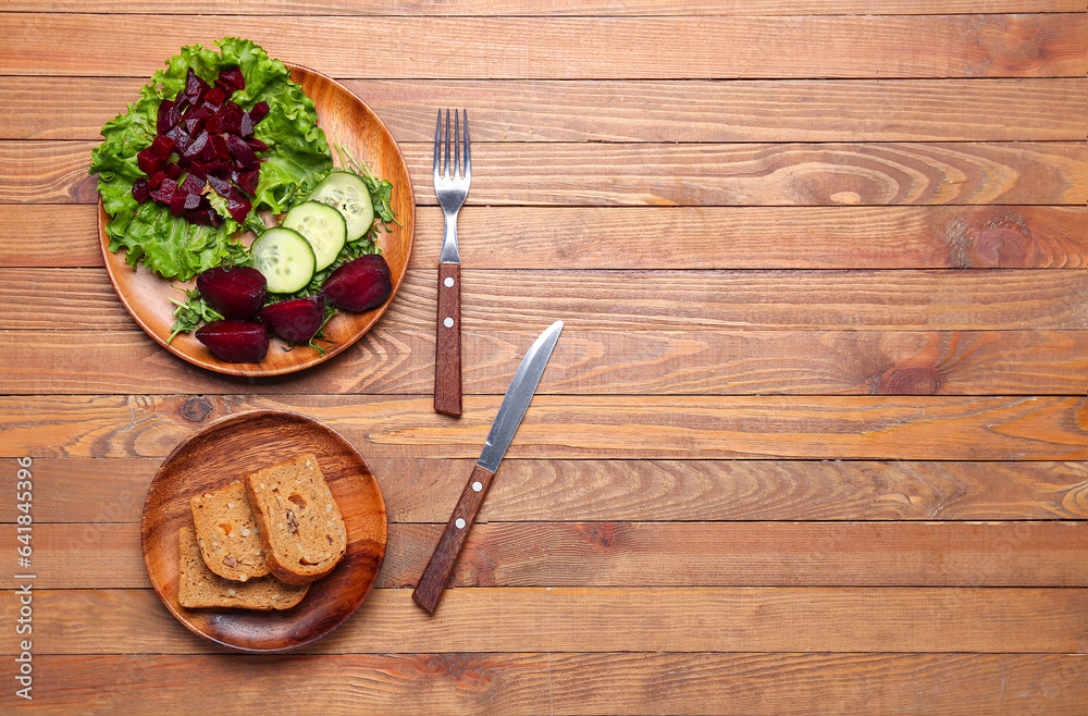 Plates of fresh vegetable salad with beet and bread on wooden background