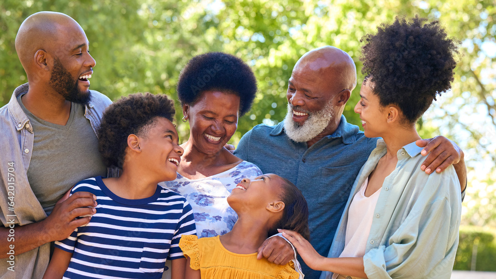 Portrait Of Multi-Generation Family Standing Outdoors In Garden Or Countryside Smiling At Camera