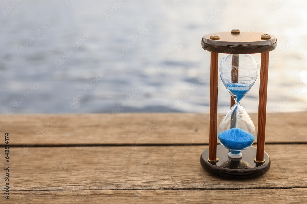 Hourglass on bridge near river, closeup