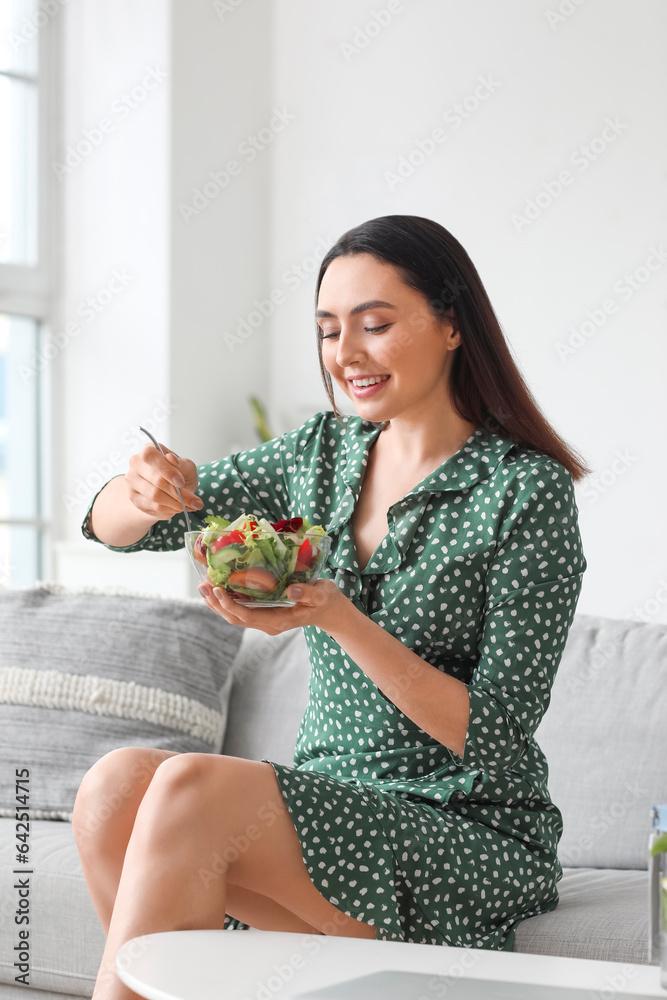 Young woman eating vegetable salad at home