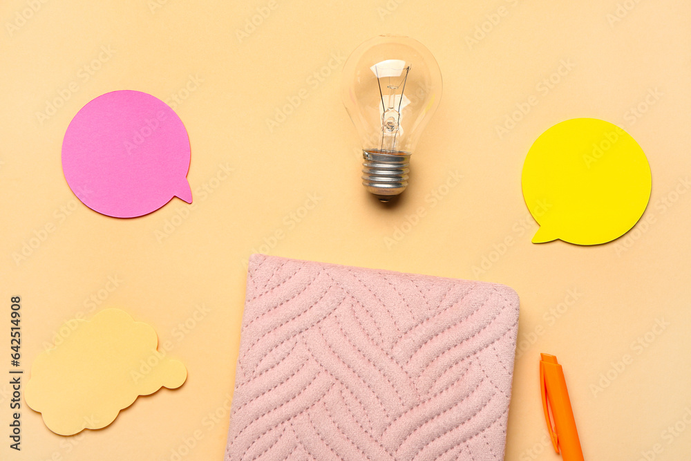 Notebook with light bulb and speech bubbles on beige background. Logic concept