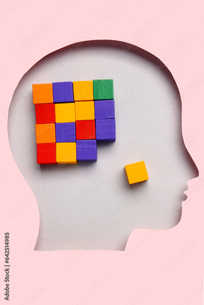 Cubes visible through cut pink paper in shape of human head on light background. Logic concept