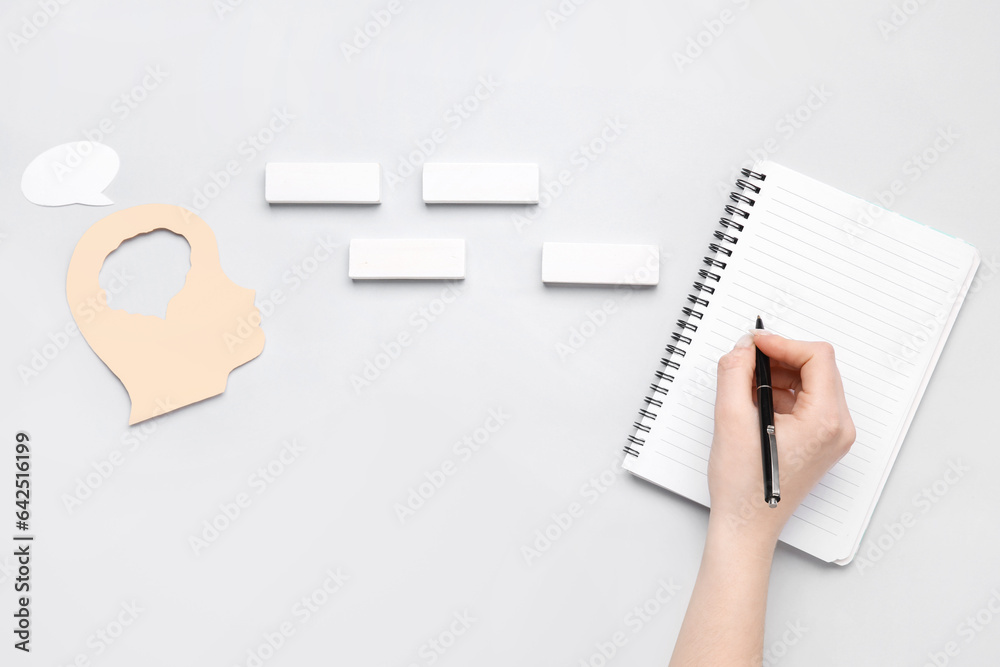 Woman writing in notebook on white background. Logic concept