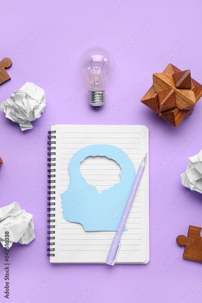 Notebook with human head, crumpled paper, light bulb and toy on lilac background. Logic concept