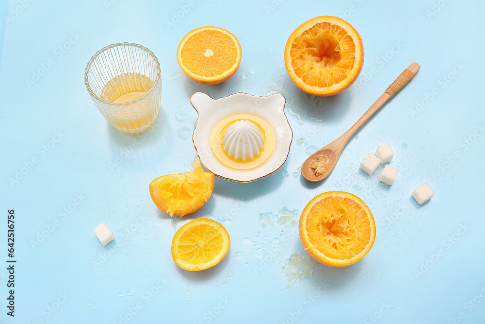 Cut orange with juicer, sugar, spoon and glass on blue background