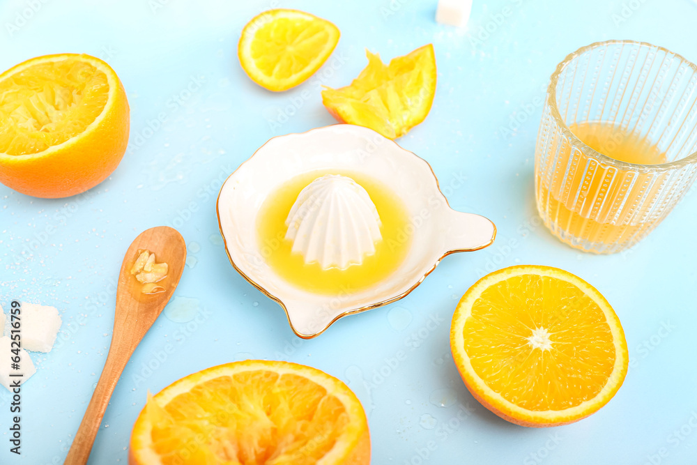 Cut orange with juicer, sugar, spoon and glass on blue background