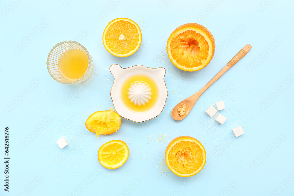 Cut orange with juicer, sugar, spoon and glass on blue background