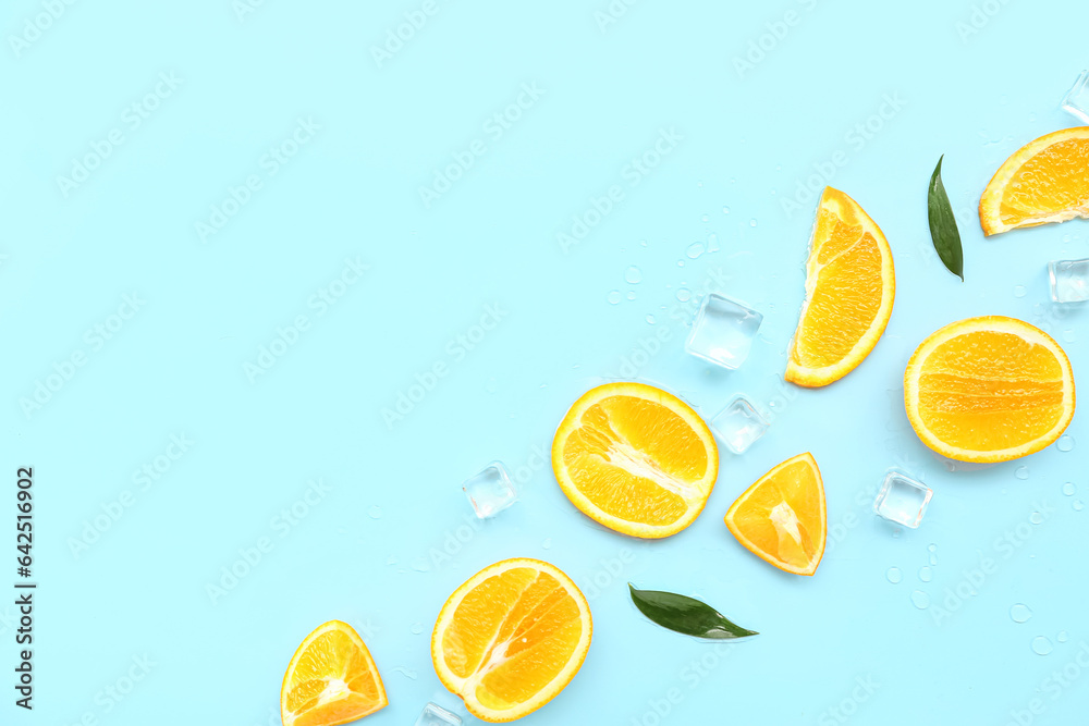 Cut orange with ice cubes and leaves on blue background