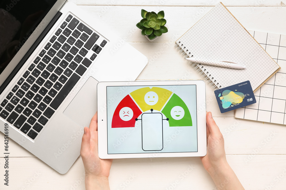 Woman holding tablet computer with experience survey on white wooden background