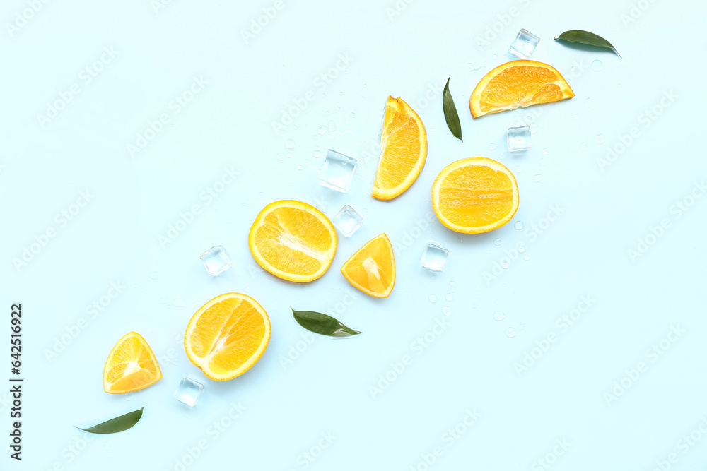 Cut orange with ice cubes and leaves on blue background