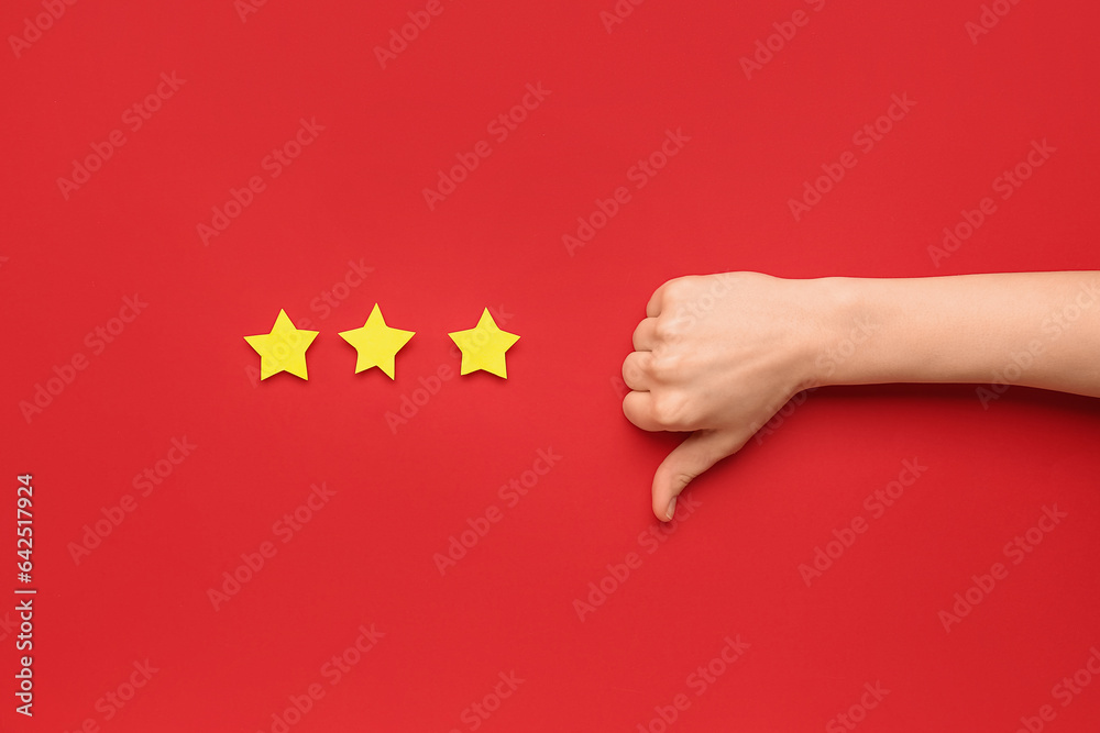 Woman showing thumb-down and three stars on red background. Customer experience concept